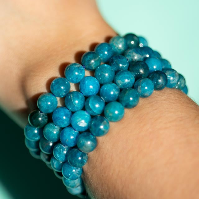 Blue Apatite beaded bracelet on a wrist with a light blue background