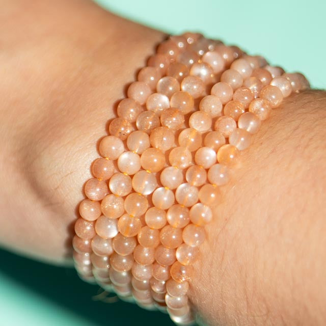Close-up of a wrist wearing a Sunstone Beaded bracelet against a light blue background
